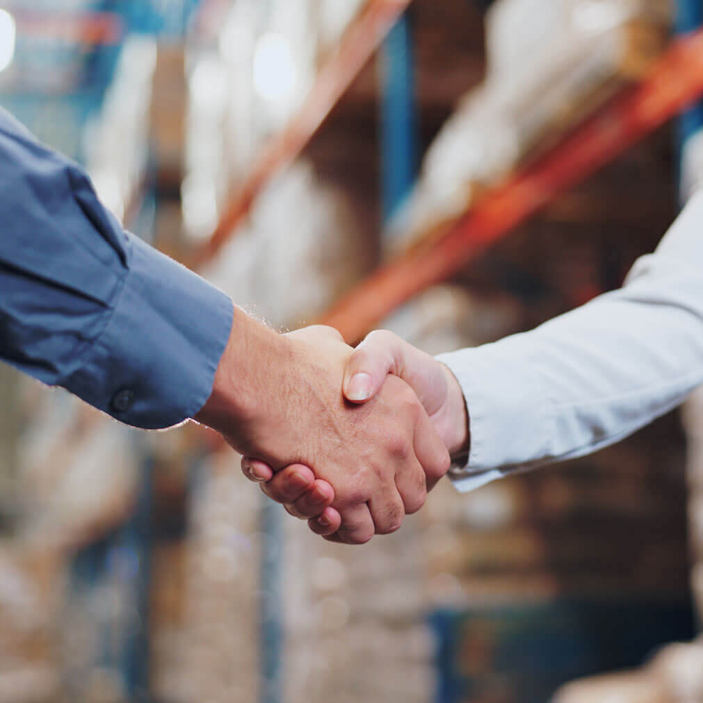 Two third party logistics providers shaking hands in a warehouse
