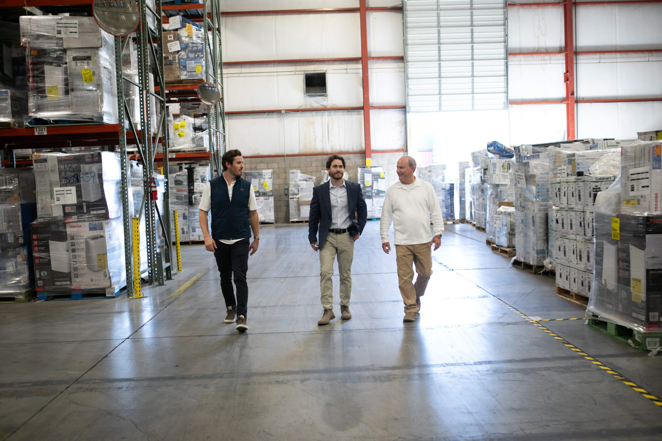Three supply chain management consultants are touring a distribution warehouse