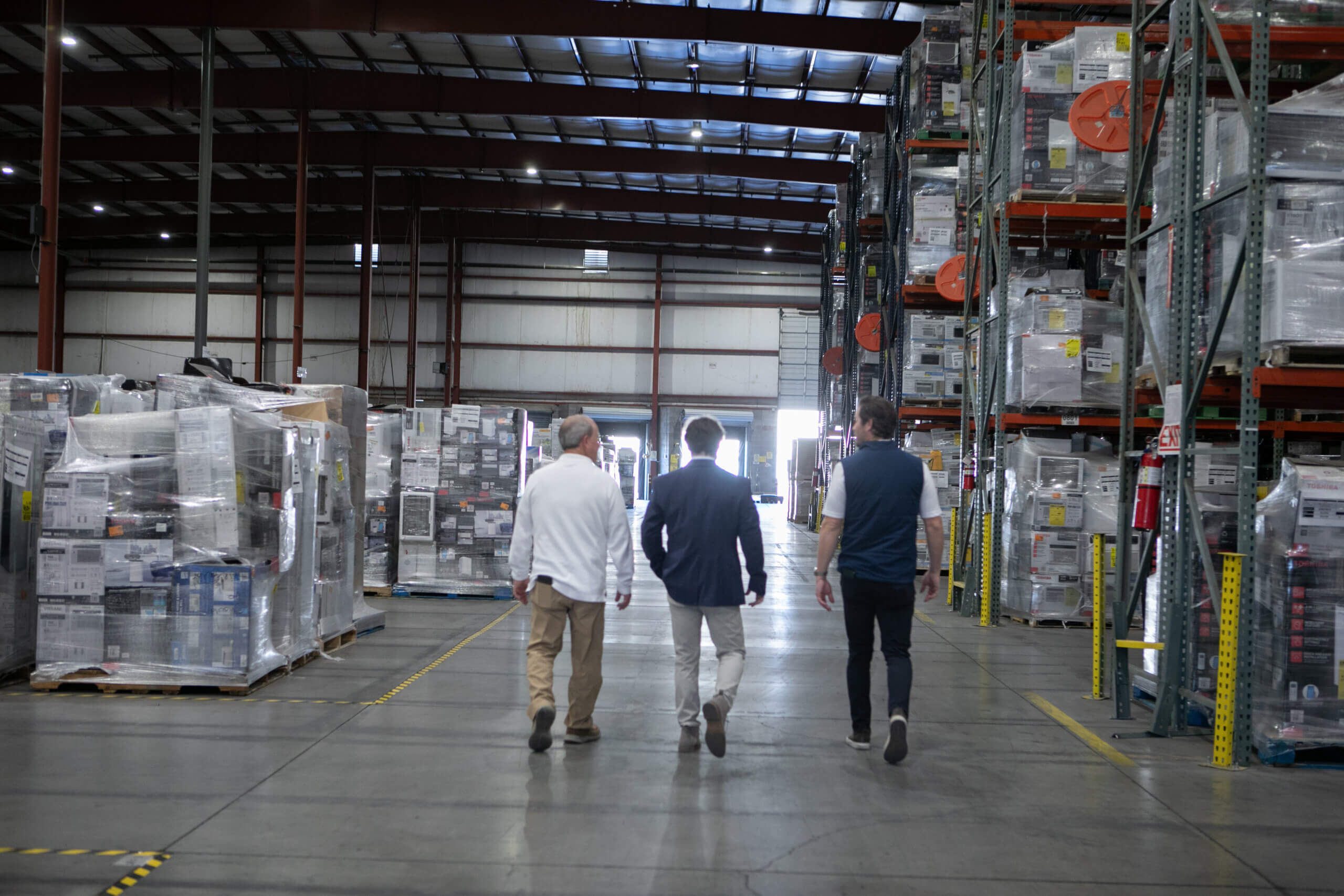 Three supply chain management consultants are touring a distribution warehouse